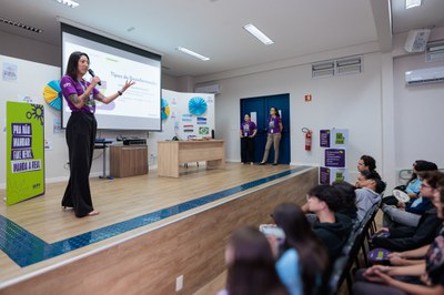 Apresentação de palestra sobre desinformação e fake news, com palestrante em palco a conduzir a exposição para um público presente num auditório.