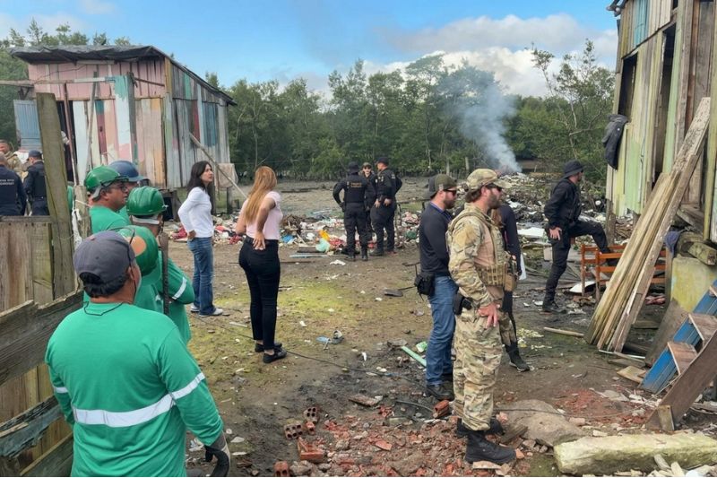 Foto mostra momento da fiscalização com diversas pessoas em um local com remoção de entulho e demolição de construções de madeira