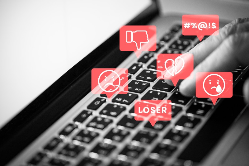 Foto mostra um teclado de computador, e emojis que indicam ofensas